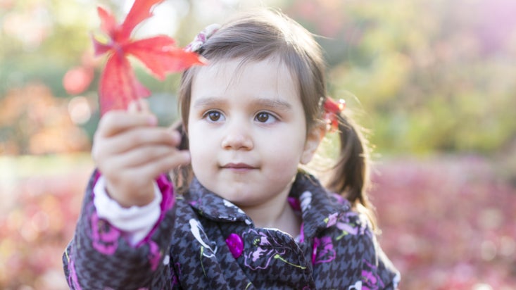 A girl playing with leaves in the autumn